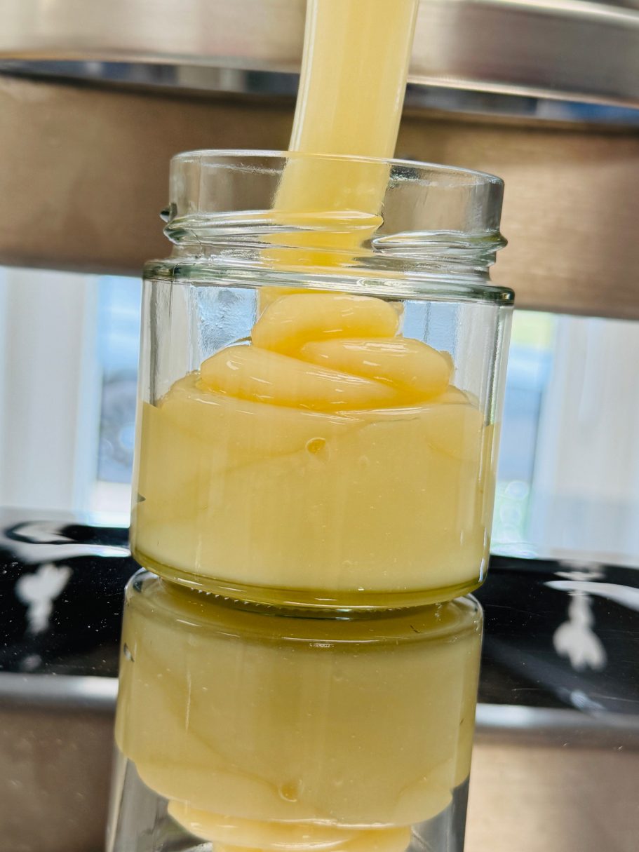 Ein Glas mit cremiger, gelber Substanz, die langsam hineingefüllt wird.