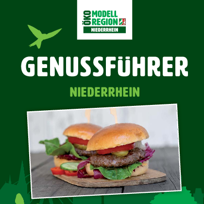 Zwei Hamburger mit frischem Gemüse auf einem Holzbrett serviert.