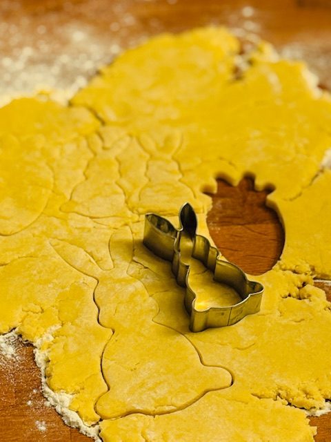 Ausstechform auf ausgerolltem Teig in Form einer Blume, umgeben von Mehl.