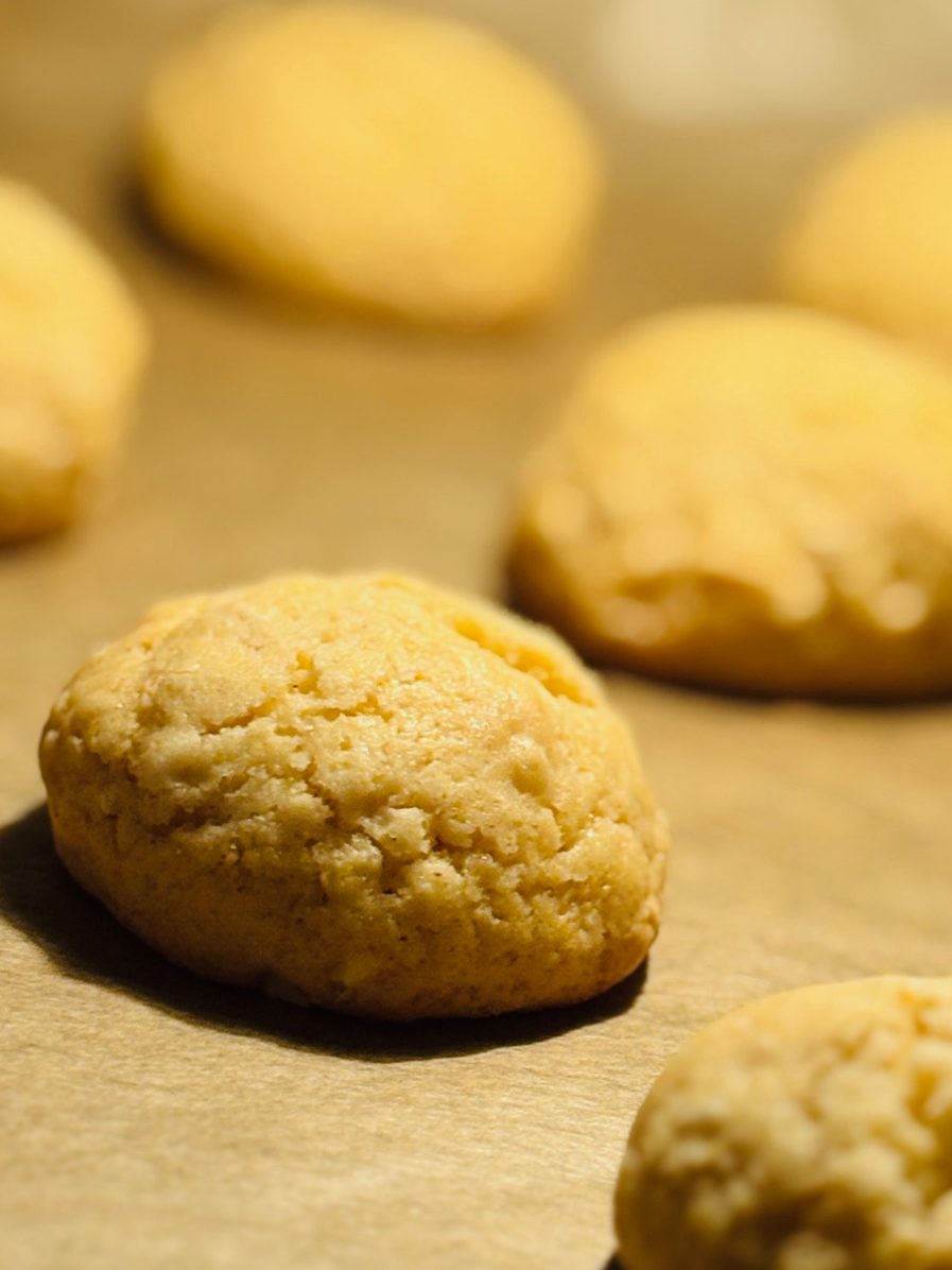 Goldene, runde Kekse auf einem Backblech, leicht unregelmäßige Oberfläche.