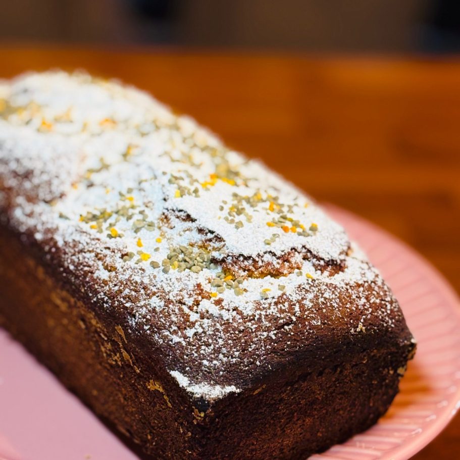 Ein frisch gebackener Kuchen mit Puderzucker und orangener Dekoration.