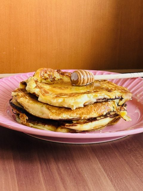 Schale mit Joghurt, Müsli, Heidelbeeren, Trauben und gewürfelter Mango.