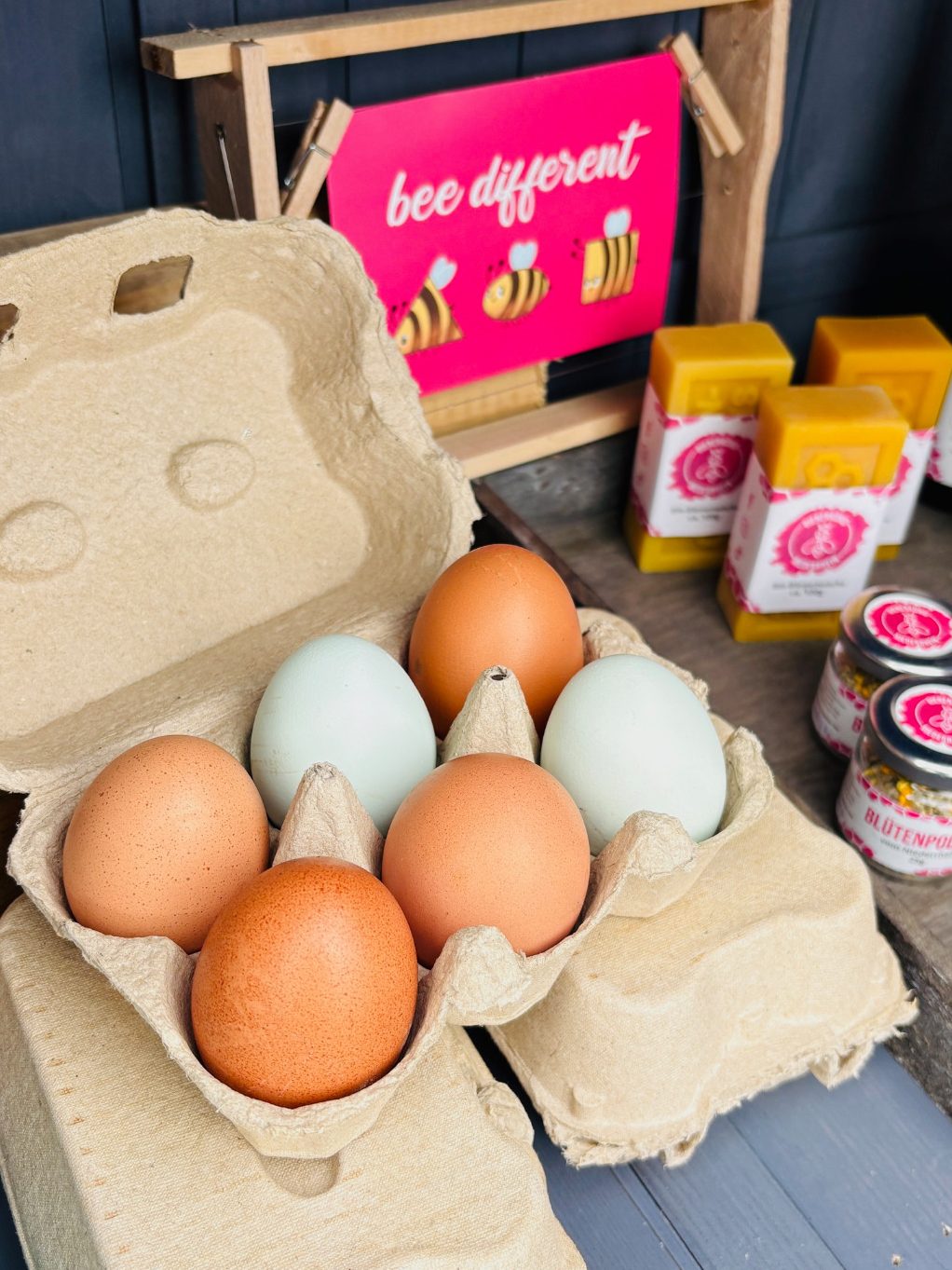 Verschiedene Flaschen und Gläser mit bunten Etiketten auf einem Holztablett.