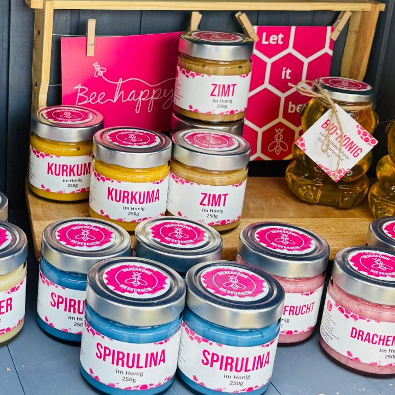 Vielfältige Gewürze in bunten Gläsern auf einem Tisch, mit dekorativen Elementen im Hintergrund.