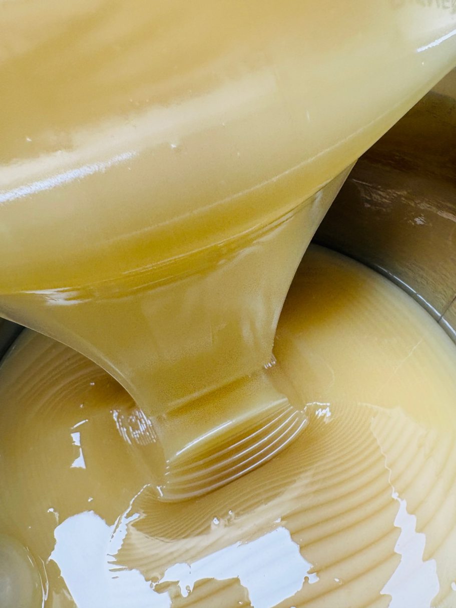 Dicke, goldene Flüssigkeit fließt aus einem Behälter in einen anderen.