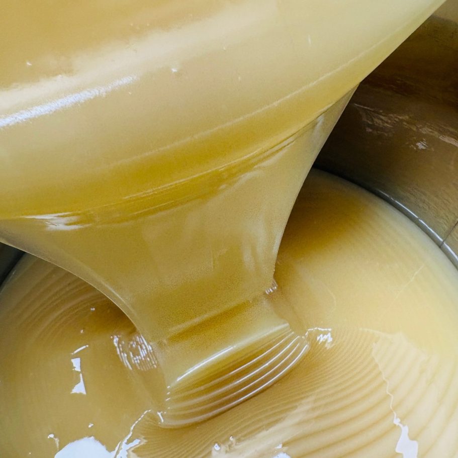 Flüssiger Honig, der aus einem Behälter in einen anderen gegossen wird.