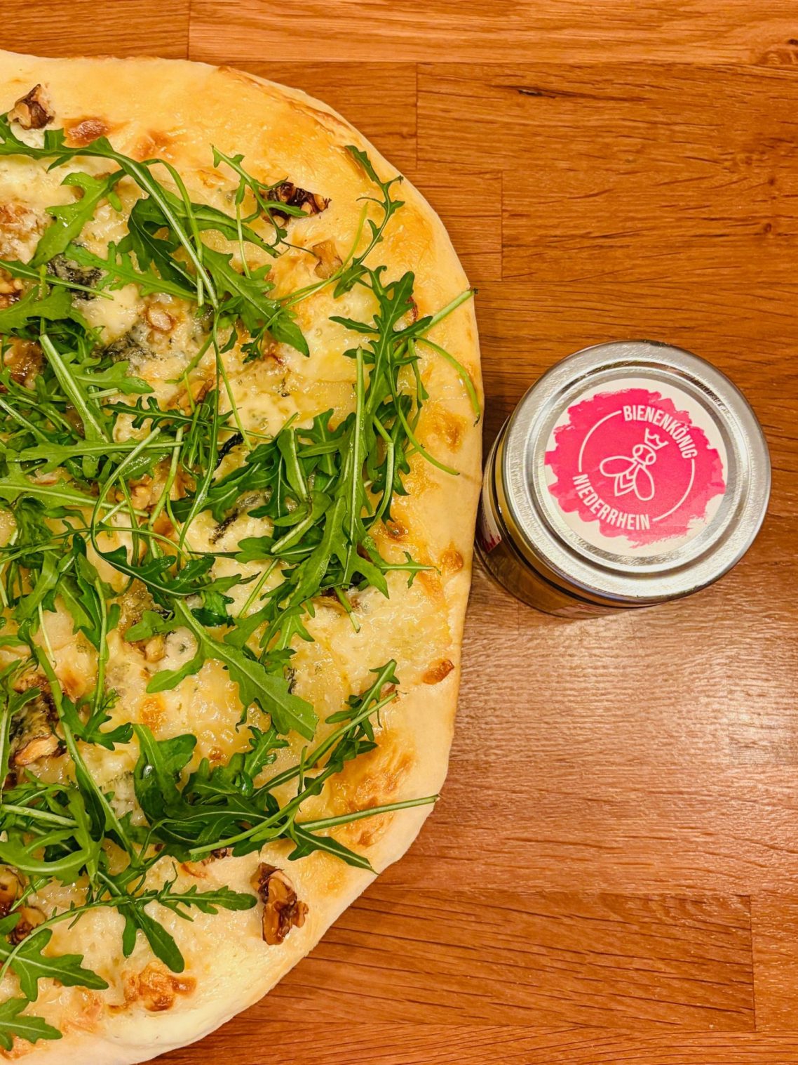 Fladenbrot mit Rucola und einer Dose mit pinkem Deckel daneben.