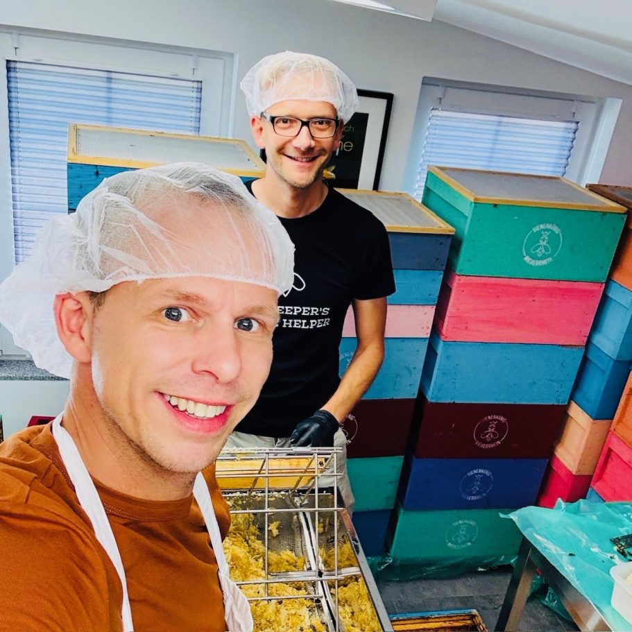 Zwei Männer in Haarnetzen, die in einer bunten Produktionsumgebung arbeiten.